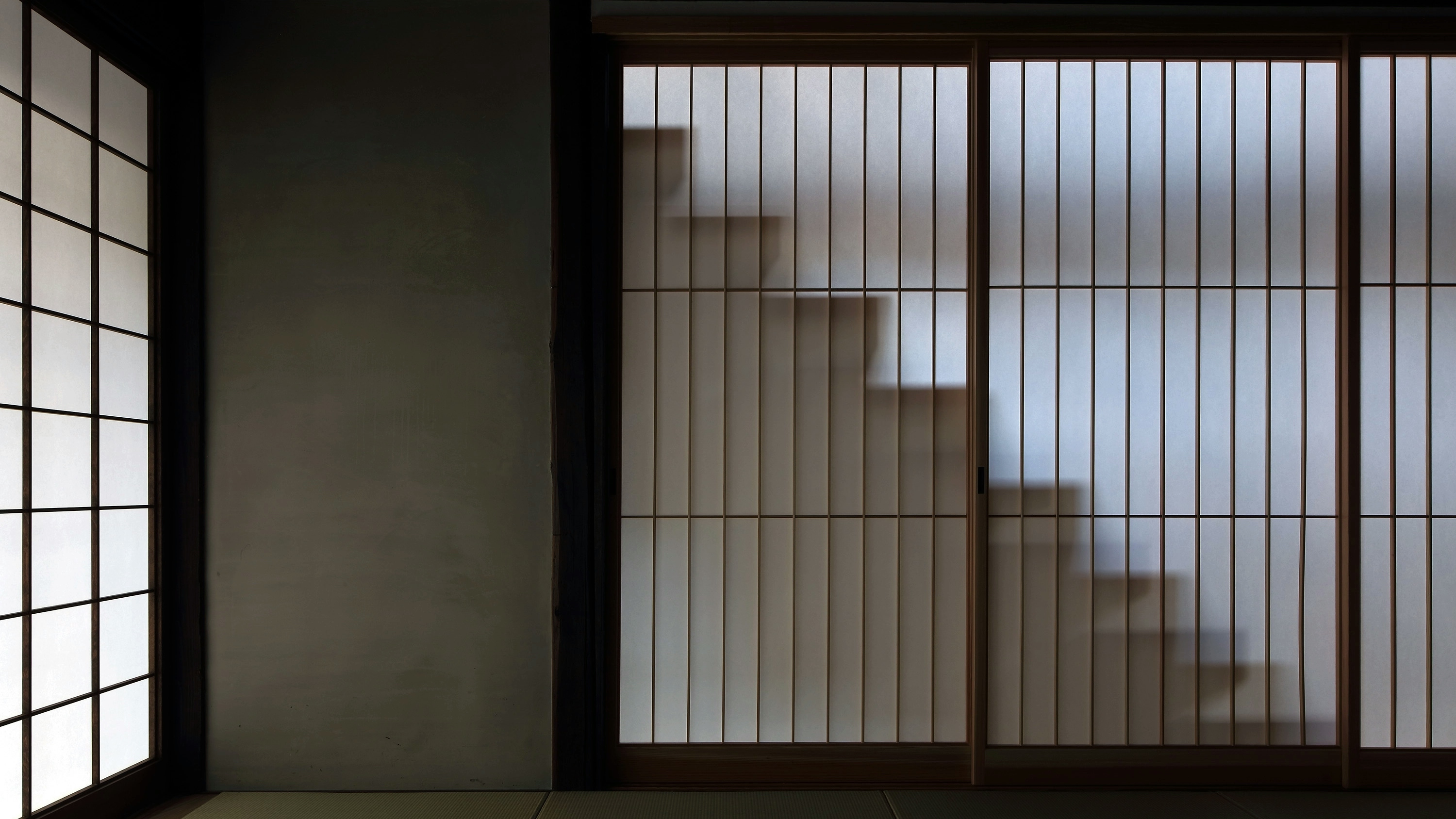 A shadow of a staircase is seen behind translucent shoji (Japanese paper screened) walls